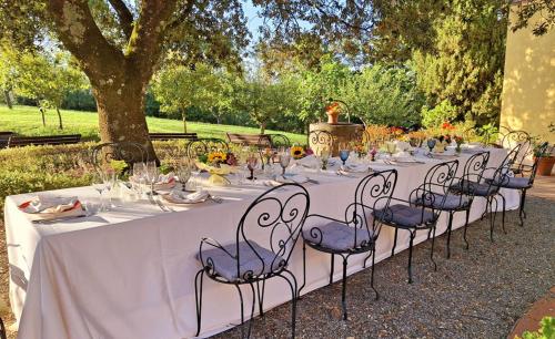 a long white table with chairs in a park at La Palazzina in Val d'Orcia in Radicofani