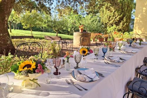 a long table with a white table cloth and flowers at La Palazzina in Val d'Orcia in Radicofani