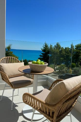 a table and chairs with a bowl of fruit on a balcony at Gloria Luxury Suites in Kallithea Halkidikis