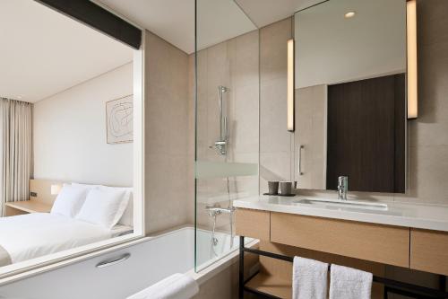 a bathroom with a tub and a sink and a bed at Shilla Stay Yeosu Expo Station in Yeosu