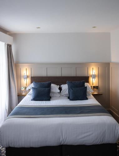 a bedroom with a large bed with blue pillows at Allerdale Court Hotel in Cockermouth