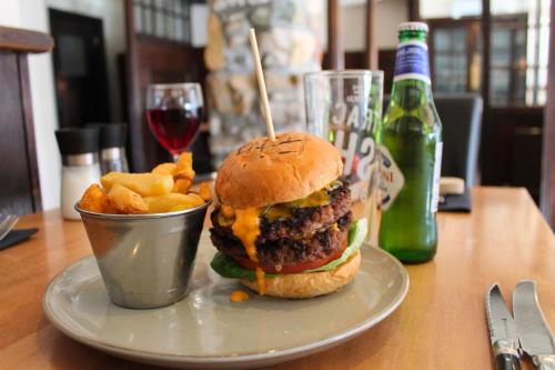 a hamburger and fries on a plate with a drink at Allerdale Court Hotel in Cockermouth
