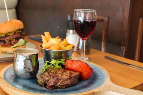a plate with a hamburger and french fries and a glass of wine at Allerdale Court Hotel in Cockermouth