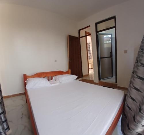 a white bed in a room with a mirror at Mihambos Apartments in Msambweni