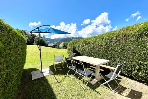 ein Tisch und Stühle mit einem Sonnenschirm im Gras in der Unterkunft Nid d'Arbois in Megève