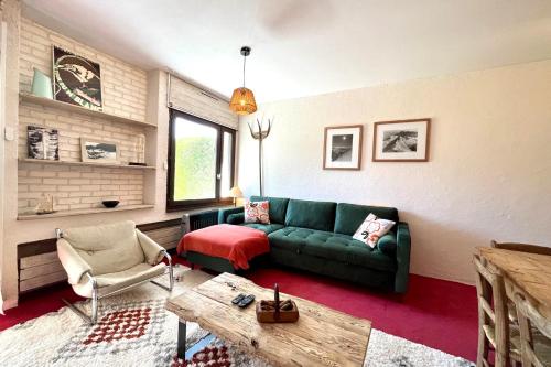 ein Wohnzimmer mit einer grünen Couch und einem Tisch in der Unterkunft Nid d'Arbois in Megève