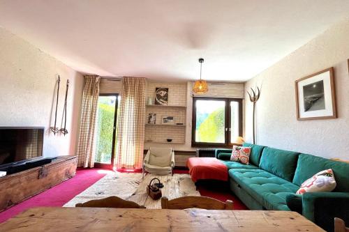 ein Wohnzimmer mit einer grünen Couch und einem Kamin in der Unterkunft Nid d'Arbois in Megève
