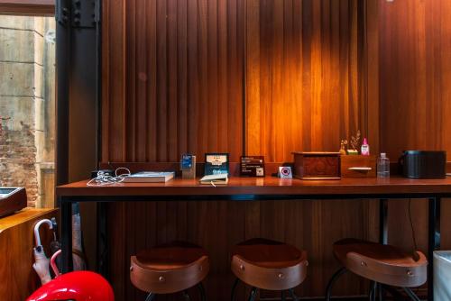 a bar with stools in a room with wooden walls at Na Tanao 1969 in Bangkok
