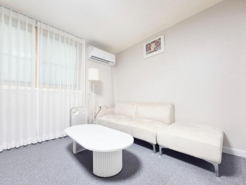 a white living room with a couch and a table at Stay B in Sŭngch'ŏn-ni