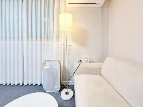 a white room with a bed and a lamp at Stay B in Sŭngch'ŏn-ni