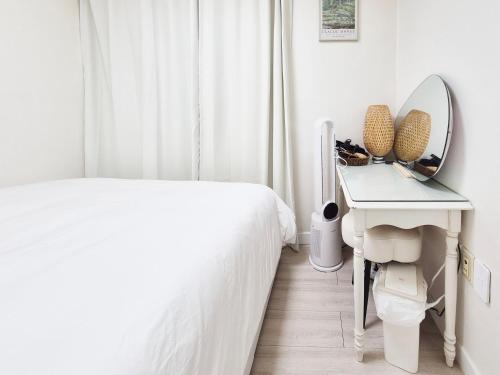 a white bedroom with a bed and a mirror at Stay B in Sŭngch'ŏn-ni
