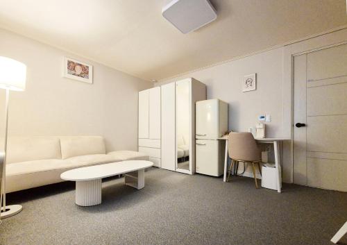 a living room with a couch and a table and a refrigerator at Stay B in Sŭngch'ŏn-ni