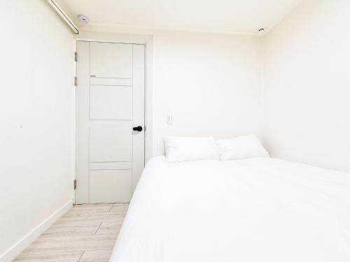 a white room with a bed and a door at Stay B in Sŭngch'ŏn-ni