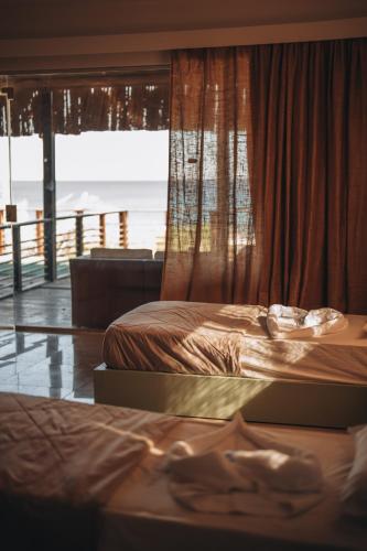 two beds in a room with a view of the ocean at The Wind Farm in Dahab