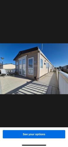 a small house on a boardwalk with a building at Whitstable Beaumont - Sleeps 6, 588 ft in Seasalter