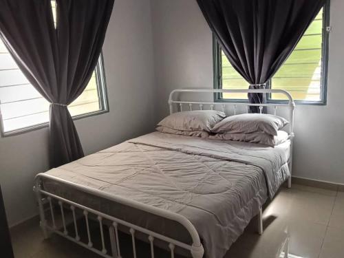 a bed in a bedroom with two windows at Sal Homestay in Slim River