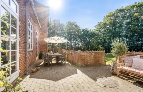 a patio with a table and an umbrella at Large Holiday Home With Pool On South Lolland Coast in Dannemare