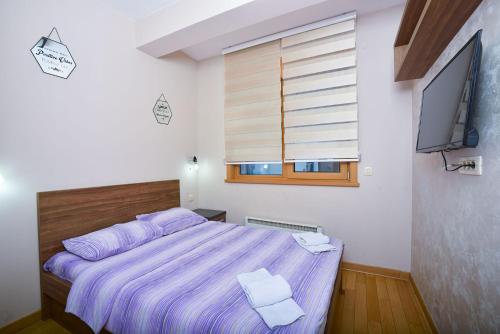 a bedroom with a purple bed and a television at Vila Mina in Zlatibor