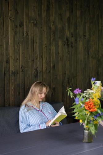 a woman sitting on a couch reading a book at Moho Будинки для відпочинку in Bukovel