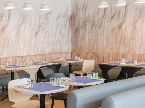 a restaurant with tables and chairs and a wall at Novotel Marne-la-Vallée Noisy-le-Grand in Noisy-le-Grand