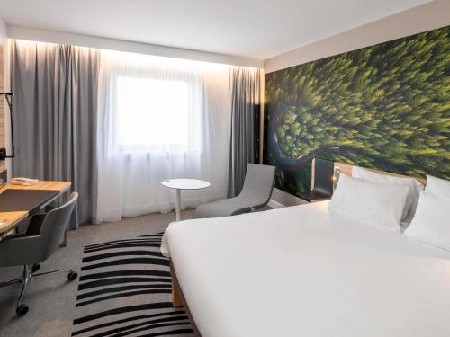 a hotel room with a bed and a painting on the wall at Novotel Marne-la-Vallée Noisy-le-Grand in Noisy-le-Grand