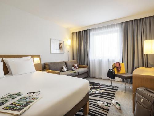 a hotel room with a bed and a couch at Novotel Marne-la-Vallée Noisy-le-Grand in Noisy-le-Grand