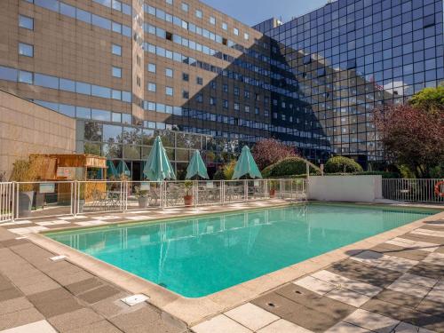 a swimming pool in front of a tall building at Novotel Marne-la-Vallée Noisy-le-Grand in Noisy-le-Grand