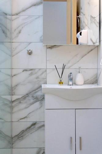 a white bathroom with a sink and a mirror at Chios Cozy Apartment 1 in Sklaviá