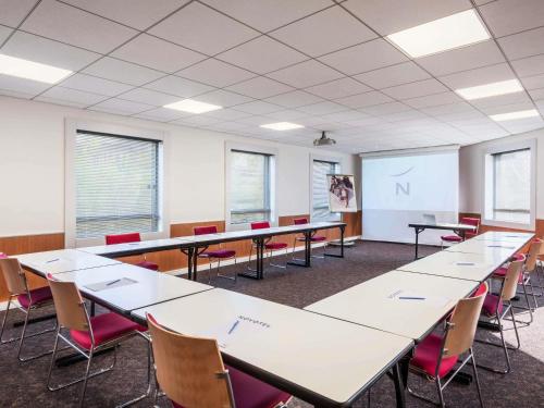 a classroom with tables and chairs and a whiteboard at Novotel Marne-la-Vallée Noisy-le-Grand in Noisy-le-Grand