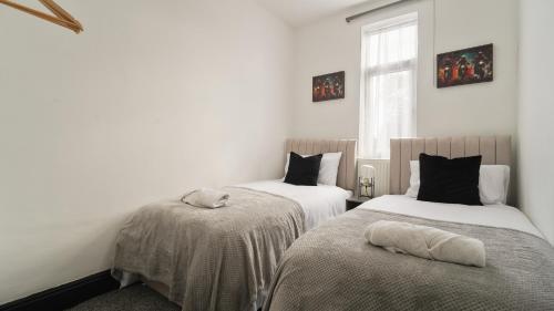 two beds in a room with white walls and a window at Cozy Sheffield Retreat 3BR, 2BA, Parking & WiFi in Sheffield