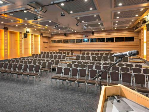 a lecture hall with chairs and a microphone at Novotel Marne-la-Vallée Noisy-le-Grand in Noisy-le-Grand