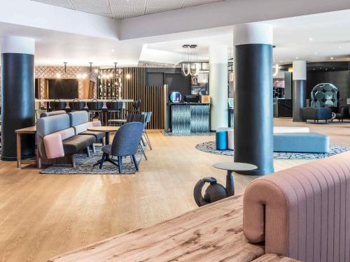 a lobby with tables and chairs and a bar at Novotel Marne-la-Vallée Noisy-le-Grand in Noisy-le-Grand