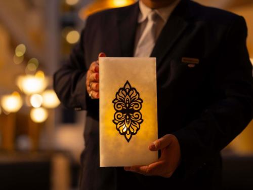 a man holding a piece of paper with a henna design on it at Sofitel Algiers Hamma Garden in Alger