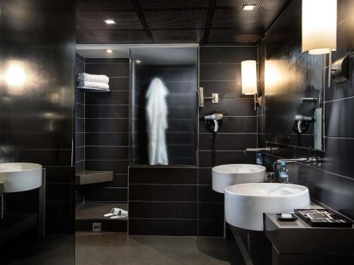 a bathroom with two sinks and a person in the shower at Sofitel Algiers Hamma Garden in Alger