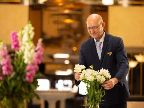 a man in a suit holding a bunch of flowers at Sofitel Algiers Hamma Garden in Alger