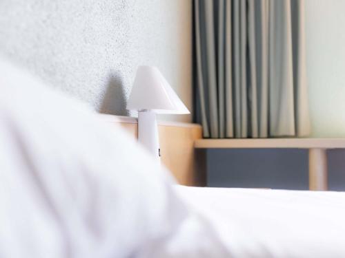 a white lamp sitting on top of a bed at ibis Vesoul in Vesoul