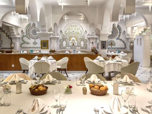 a dining room with white tables and chairs and a restaurant at Sofitel Algiers Hamma Garden in Alger