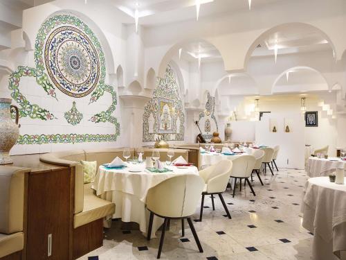 a restaurant with white tables and chairs and a floral wall at Sofitel Algiers Hamma Garden in Alger