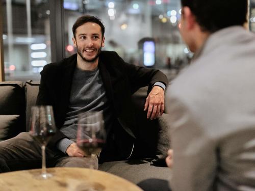 a man sitting on a couch with a glass of wine at ibis Vesoul in Vesoul