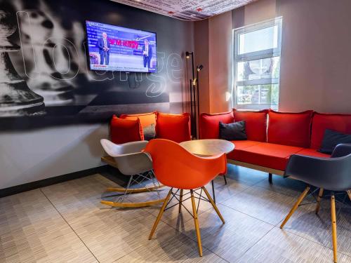 a waiting room with a red couch and chairs at ibis Vesoul in Vesoul