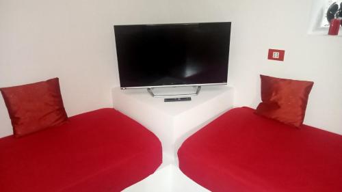 two red chairs in a room with a flat screen tv at Sally's House in Venaria Reale
