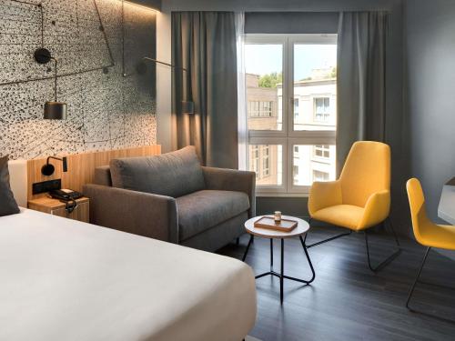 a hotel room with a bed and chairs and a window at Mercure Montpellier Centre Antigone in Montpellier