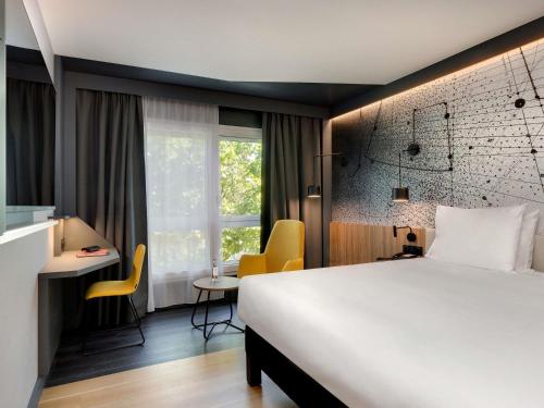 a hotel room with a bed and a desk and a window at Mercure Montpellier Centre Antigone in Montpellier