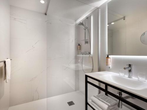 a white bathroom with a shower and a sink at Mercure Montpellier Centre Antigone in Montpellier