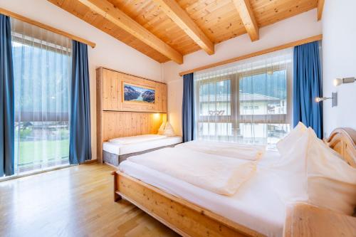 a bedroom with a large bed and large windows at Ferienwohnungen Haus der Mitte in Mayrhofen