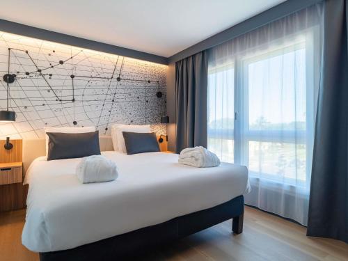 a large bed in a room with a large window at Mercure Montpellier Centre Antigone in Montpellier