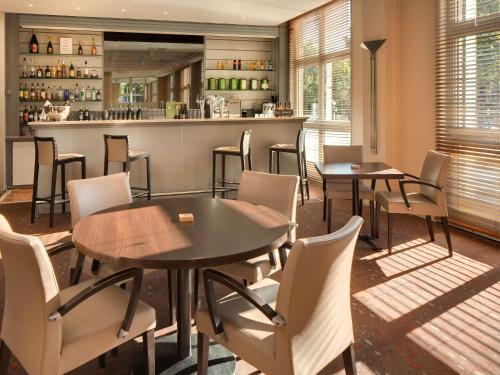 a restaurant with tables and chairs and a bar at Mercure Montpellier Centre Antigone in Montpellier