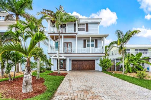una casa blanca con palmeras delante en 571 Seabatical- Canal Front With Pool! home, en Fort Myers Beach