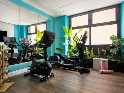 a gym with several exercise bikes in a room with plants at Cerretani Hotel Firenze - MGallery Collection in Florence
