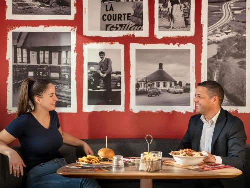 a man and a woman sitting at a table with food at Ibis Marne la Vallée Noisy in Noisy-le-Grand